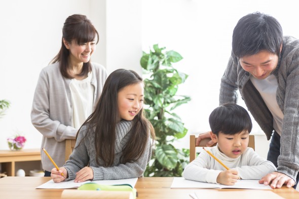 勉強する子供と勉強を見る親