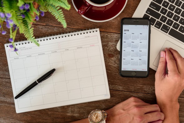 SEPTEMBER 17, 2018: Working table top with organizer for monthly planing with a pen, Macbook air, Iphone 8 plus and a cup of black coffee